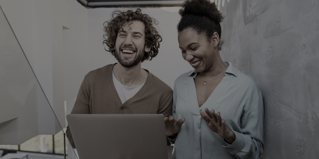 Two developers laughing while looking at a laptop together